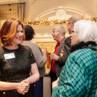 Laura Aikens smiling and chatting with woman at party